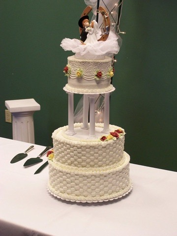 Three-tier white wedding cake with basketweave piping, pillars and a bride and groom topper