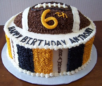 Round birthday cake topped with a chocolate football in black and gold team colors