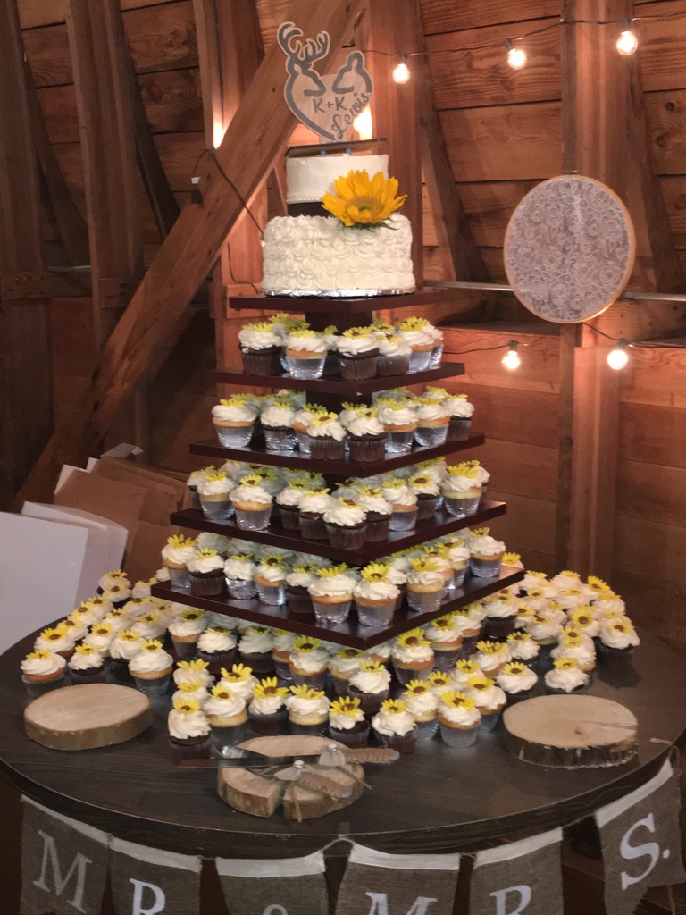Rustic barn wedding cupcake tower with a sunflower-topped cutting cake