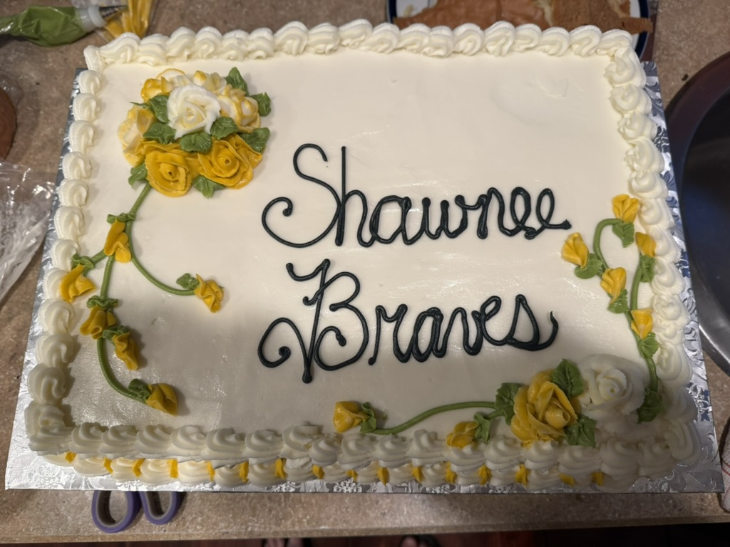White sheet cake with yellow piped roses and script lettering