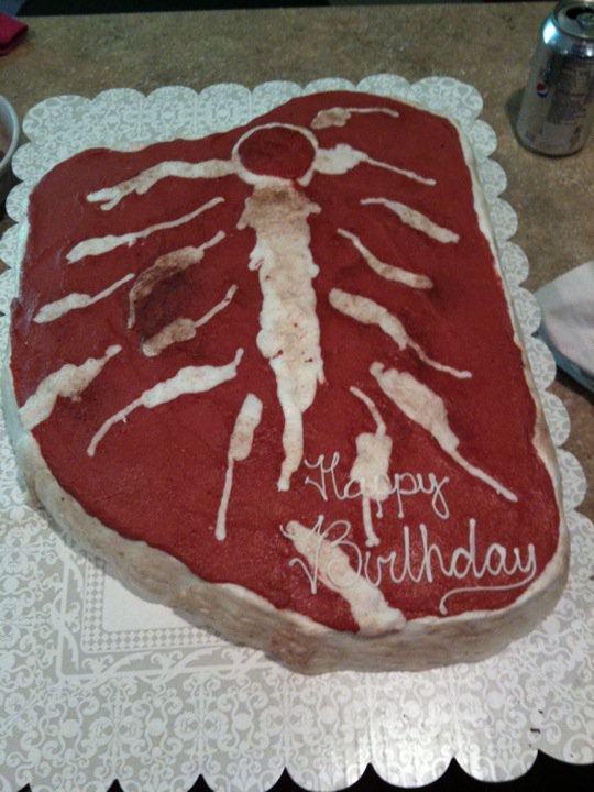 Red shaped birthday cake with white piped design on a lace doily