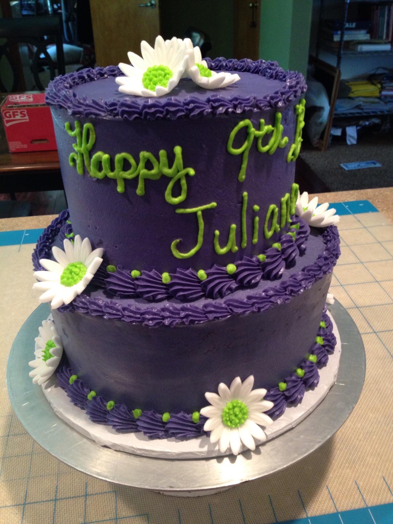 Two-tier purple birthday cake with white daisies and lime green lettering