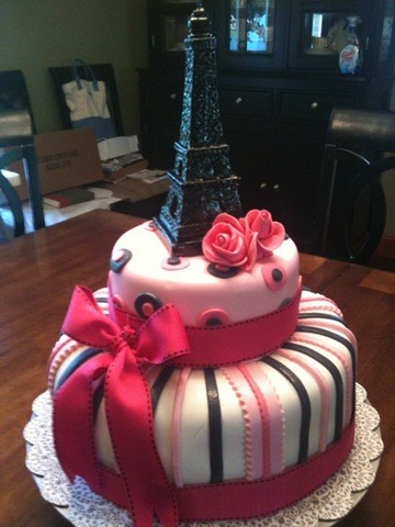 Two-tier pink, black and white striped cake with a ribbon bow and Eiffel Tower topper