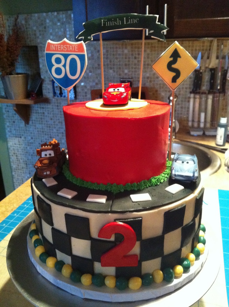 Two-tier race car birthday cake with a checkered flag tier and toy cars