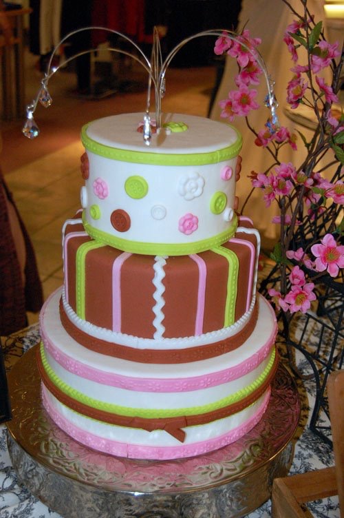 Three-tier pink, brown and lime striped cake with a wire topper